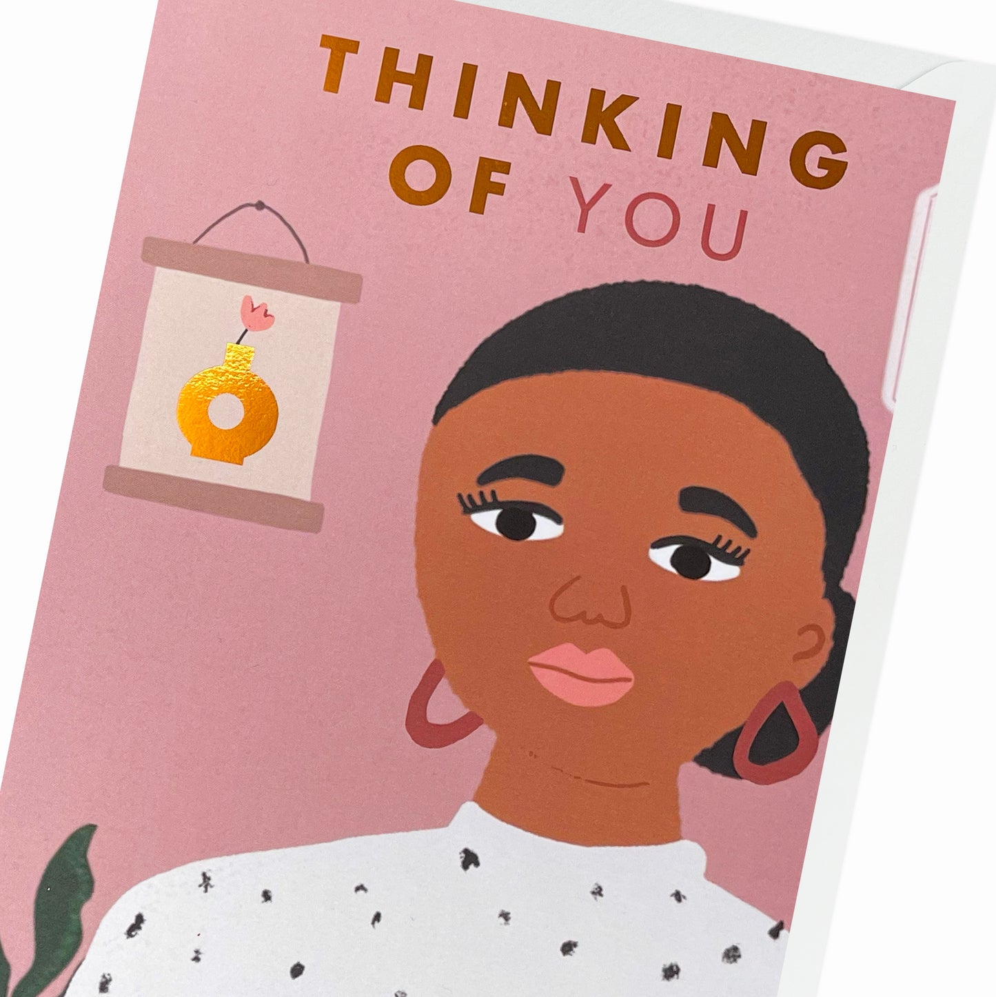Close up of a Black Woman relaxing at home in a spotty white shirt, surrounded by an aloe vera plant and a picture on the wall. Black Greeting Card