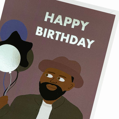 A close up of a Black Man wearing a brim hat, holding birthday balloons. Black Birthday Card